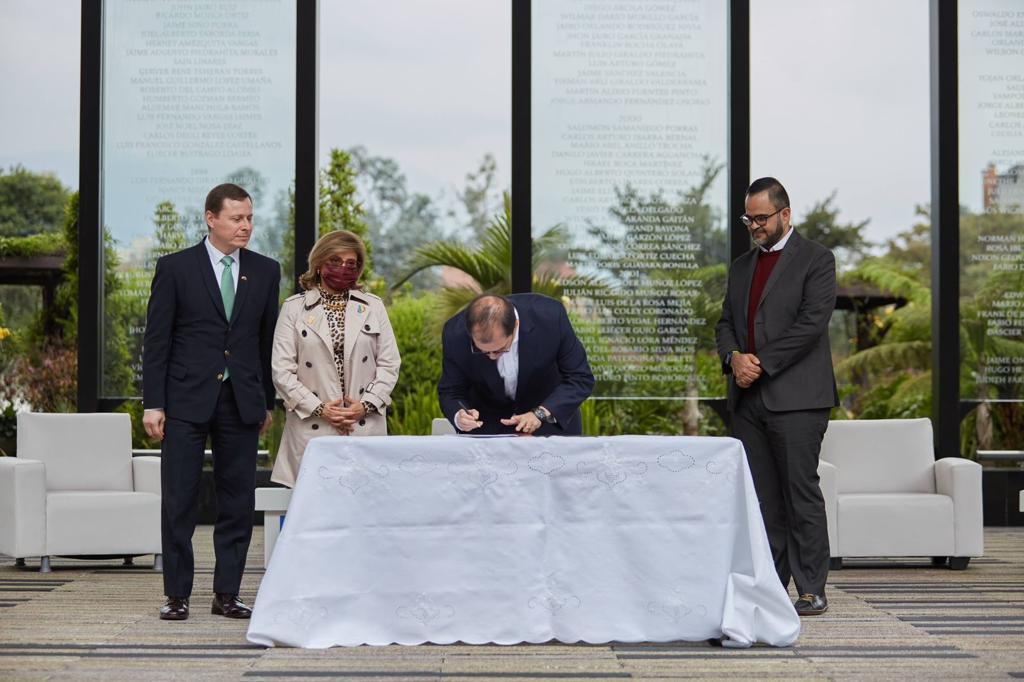 En la imagen aparecen cuatro personas, una de ellas, el Fiscal General de la Nación, firmando un documento.
