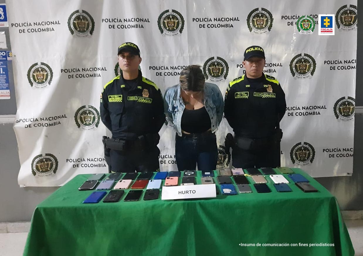 En la fotografía se aprecia a la procesada esposada, custodiada por dos uniformados de la Policía Nacional. Está en una mesa con los 38 celulares que habría hurtado la mujer durante un evento del Carnaval de Barranquilla.