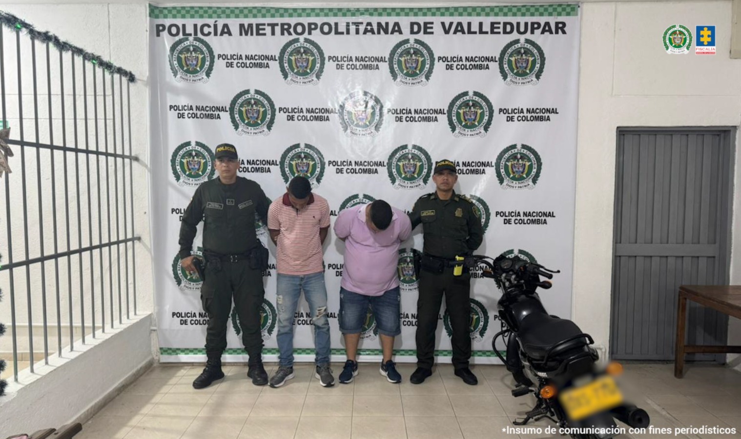 Los capturados se encuentran de frente y  custodiados por dos uniformados de la Policía Nacional. En la foto se ve de fondo un backing de la Policía Nacional y una de las motos utilizadas para cometer el hurto.