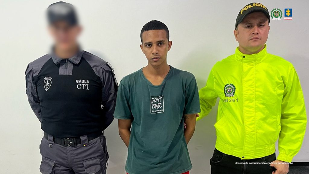 En la imagen aparece una persona de suéter verde entre un uniformado del CTI y la Policía Nacional.