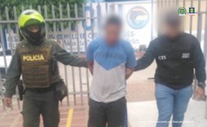 En la imagen aparece una persona, de camiseta blanca con azul, entre un policía y un investigador del CTI.