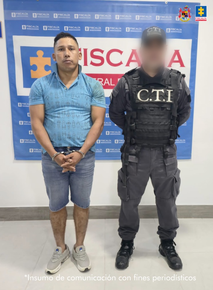 En la imagen aparece una persona detenida, de bermuda de jean y suéter azul, junto a un uniformado del CTI.