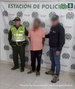 En la imagen aparece una persona de suéter rosado entre un policía y un uniformado del CTI.