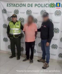 En la imagen aparece una persona de suéter rosado entre un policía y un uniformado del CTI. 
