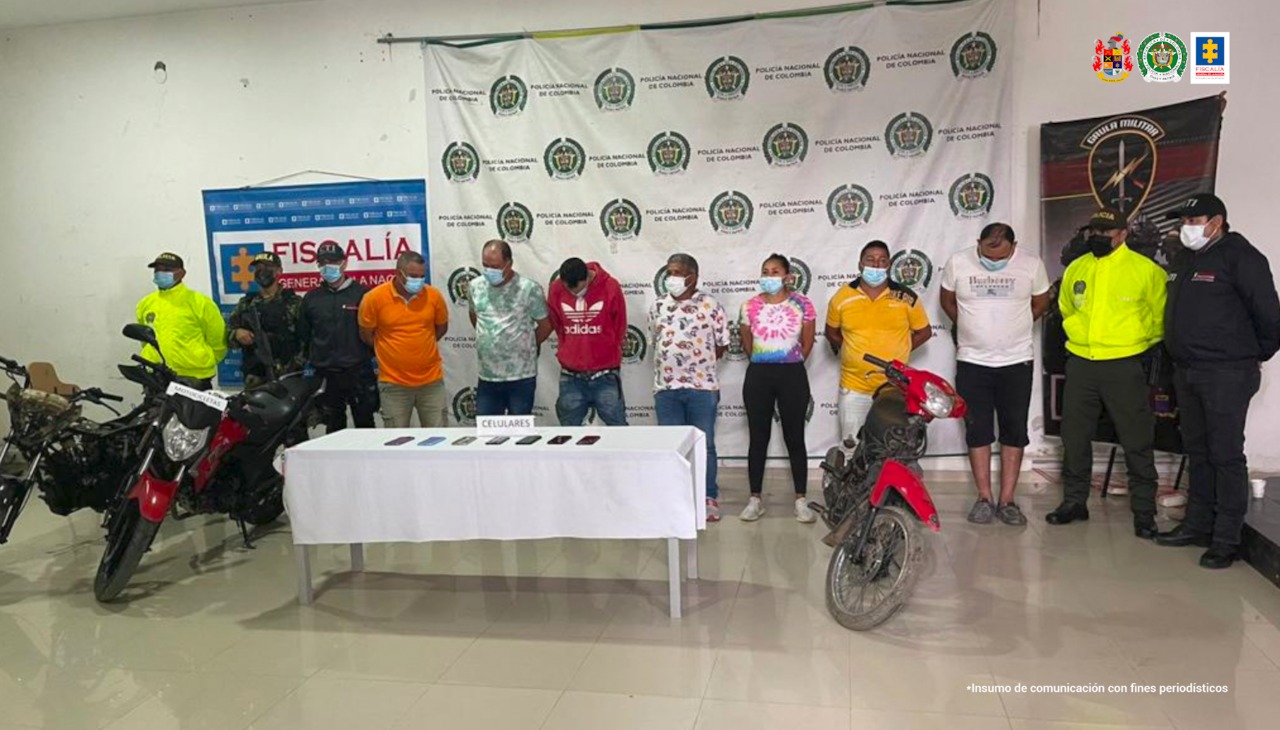 En la imagen se aprecian 6 hombres detenidos y una mujer, entre investigadores de la Fiscalía y la Policía y frente a tres motocicletas.