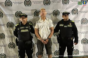 En la imagen aparece una persona de suéter blanco entre dos uniformados de la Policía.