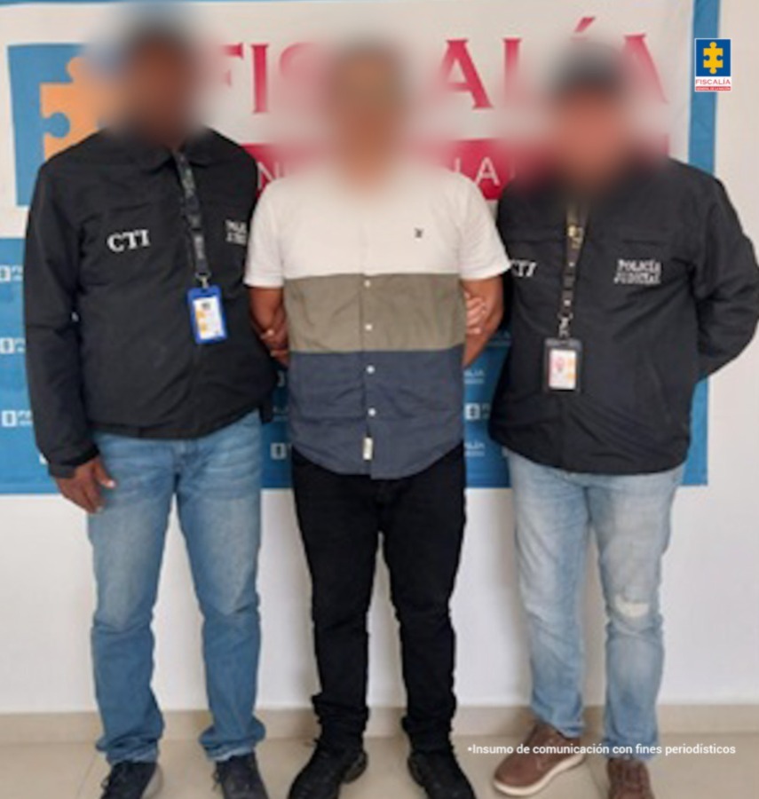 En la imagen aparece una persona de camisa de colores azul, gris y blanca, entre dos uniformados del CTI.