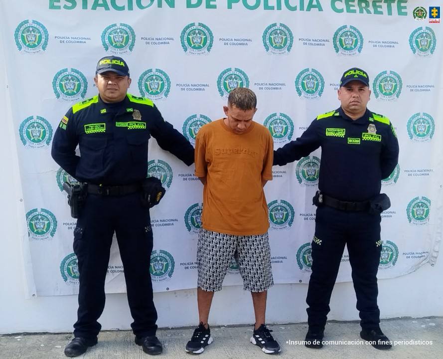 En la imagen aparece una persona en bermuda y suéter naranja, entre dos uniformados de la Policía Nacional.