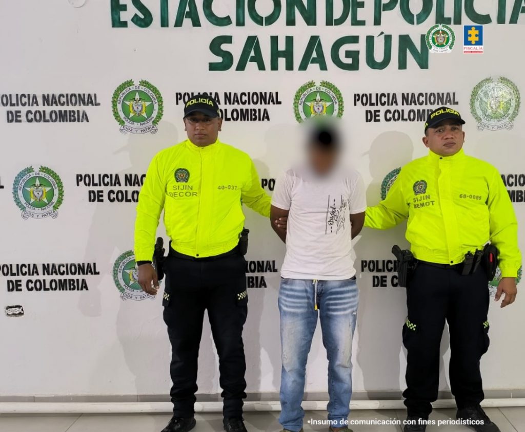 En la imagen aparece una persona con suéter blanco entre dos uniformados de la Policía.
