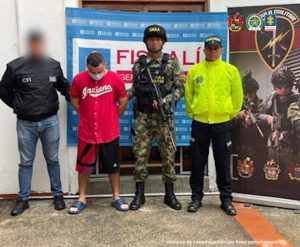 En la imagen aparece una persona de suéter rojo detenida entre uniformados de la Policía, el Ejército y la Fiscalía.