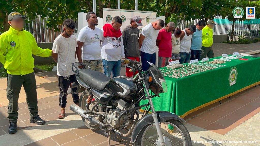 En las fotografías aparecen nueve personas de pie, con los brazos hacía atrás, custodiado por dos uniformados de la Policía Nacional. Delante de ellos hay una mesa con mantel verde donde están las dosis de drogas incautadas y una motocicleta y detrás de ellos hay un pendón de la Policía Nacional.