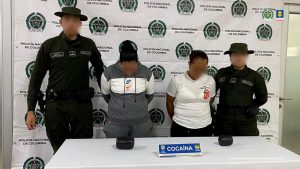 En la foto están dos mujeres de pie, con las cabezas agachadas, con los brazos atrás, una se encuentra con sudadera gris, la otra con camiseta blanca y pantalón negro, custodiadas por dos uniformados de la Policía Nacional. Delante de ellos hay una mesa con la droga incautada.