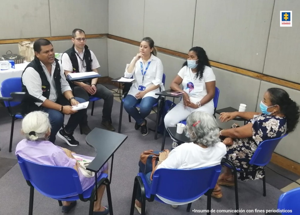 En la imagen aparecen 7 personas, dos hombres con chalecos negros que son de la Fiscalía, una mujer con carnet azul de la Unidad de Víctimas y 4 mujeres familiares de la víctima.