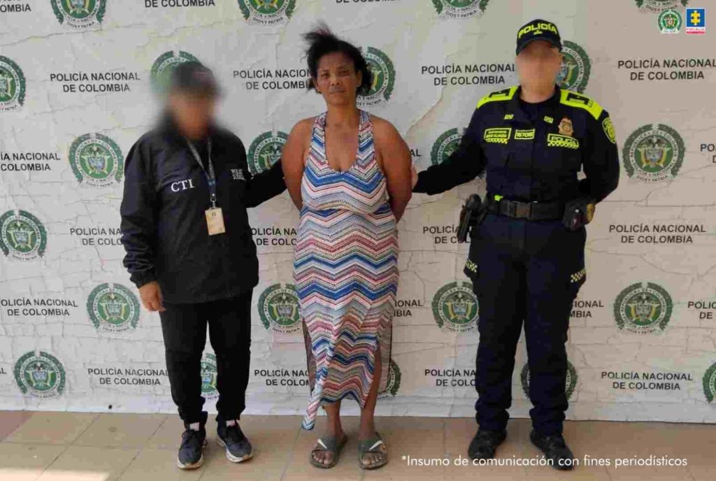 En la foto está el medio cuerpo de una mujer morena, de cabellos negros crespos recogido, boca, nariz y ojos grandes, se encuentra vestida con una camiseta roja y está sentada en el interior de una oficina asistiendo virtualmente a la audiencia en la que se le procesó.