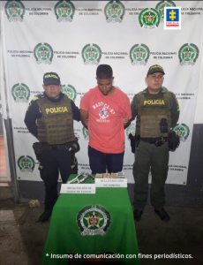 En la fotografía aparece un  hombre vestido de tez morena, vestido de camiseta roja con jean, custodiado por dos agentes de la Policía Nacional. Detrás de ellos está un pendón de esa institución y delante de ellos aparece una mesa con el arma de fuego y el dinero que se le incautó en la captura.