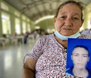 En la imagen aparece una persona con la foto de un familiar en la mano.
