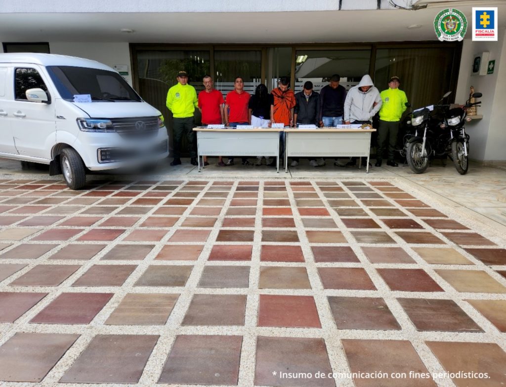 Fiscal Martha Mancera, Martha Mancera, Fiscal Mancera En la fotografía se aprecian de pie a siete de los presuntos implicados en tráfico de estupefacientes. A lado y lado de ellos hay uniformados de la Policía Nacional. Delante de ellos hay dos mesas y sobre ellas varios elementos. Asimismo, a la derecha hay una camioneta blanca y al lado izquierdo dos motocicletas.