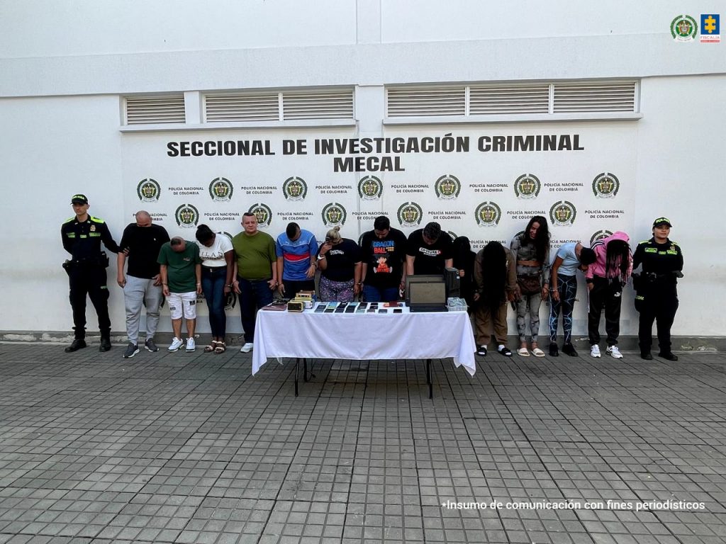 En la fotografía aparecen en hilera, de pie y esposados entre sí los presuntos integrantes de ‘Los Burke’. A sus extremos hay uniformados de la Policía Nacional. Delante de ellos hay una mesa con mantel blanco y sobre ella se aprecian varios teléfonos celulares, computadores portátiles y otros elementos. En la parte posterior hay un pendón de la Policía.