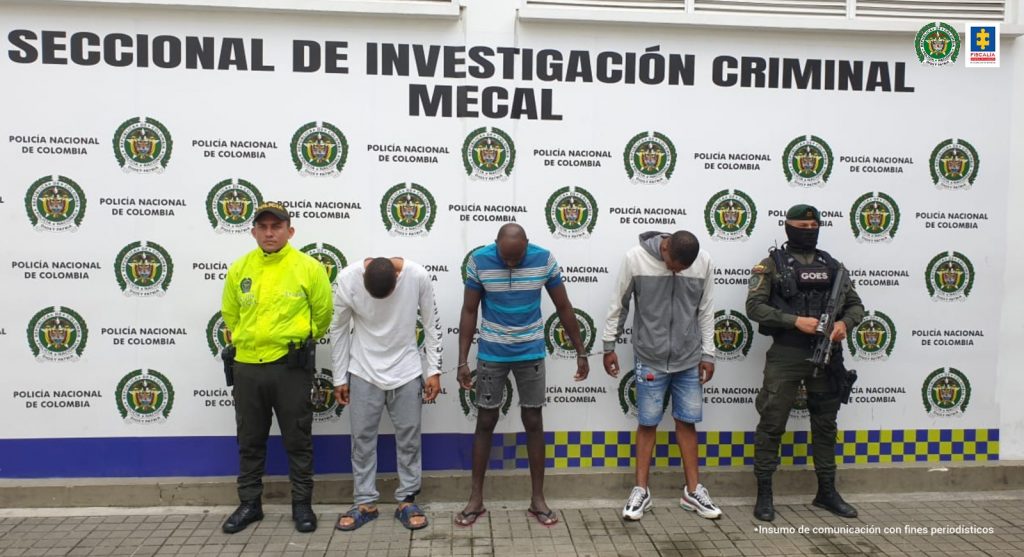 En la foto aparecen de pie y agachados los presuntos implicados en el hurto a la Oficina de Instrumentos Públicos de Cali. A lado y lado de ellos hay uniformados de la Policía Nacional. Detrás de ellos hay un pendón institucional de la Policía.