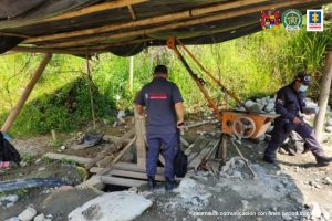 En la foto aparecen servidores del CTI de la Fiscalía del Cauca en un ‘cambuche’ armado con guadua y plásticos negros. Se aprecia maquinaria, y un socavón en la tierra y tablas.