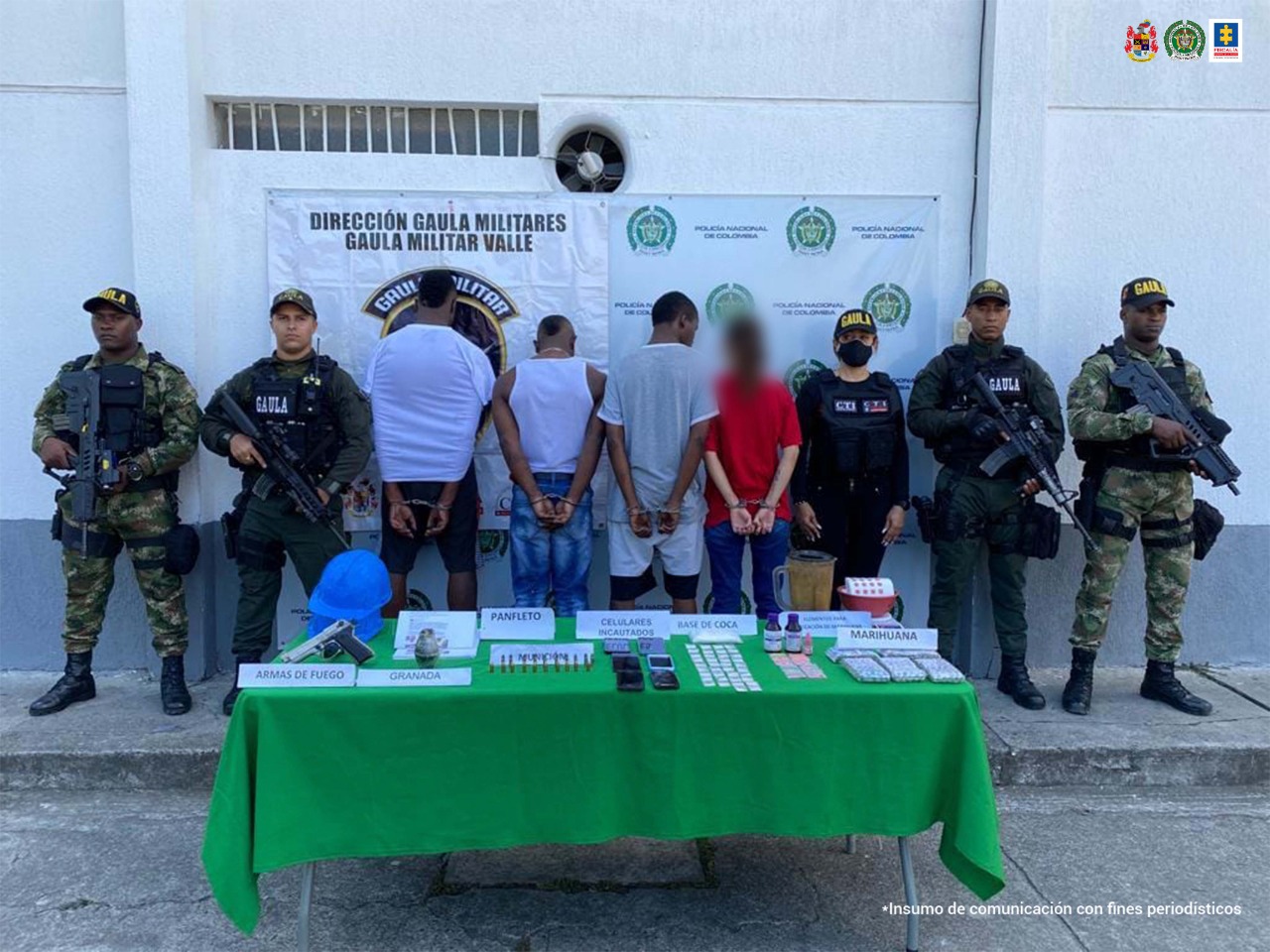 En la foto aparecen de espalda los 3 presuntos integrantes de ‘La Oficina’, tres hombres y una mujer. A lado y lado de ellos hay uniformados del Gaula Policía y Gaula Militar. Delante de ellos hay una mesa con mantel verde con los elementos incautados durante la diligencia de registro y allanamiento. Detrás de ellos hay un pendón institucional de la Policía Nacional.