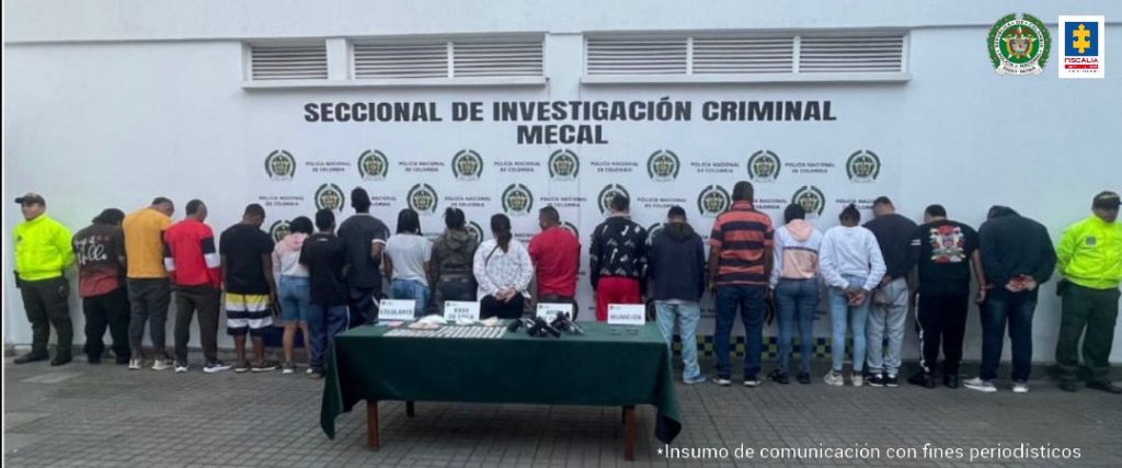 En la fotografía aparecen de espaldas a la cámara y en hilera los presuntos integrantes de ‘Las Palmas´ y ‘La Arboleda’. A lado y lado de ellos hay uniformados de la Policía Nacional. En la parte delantera hay una mesa con mantel verde y sobre varios elementos incautados. En la parte posterior de ellos hay un pendón institucional de la Policía.