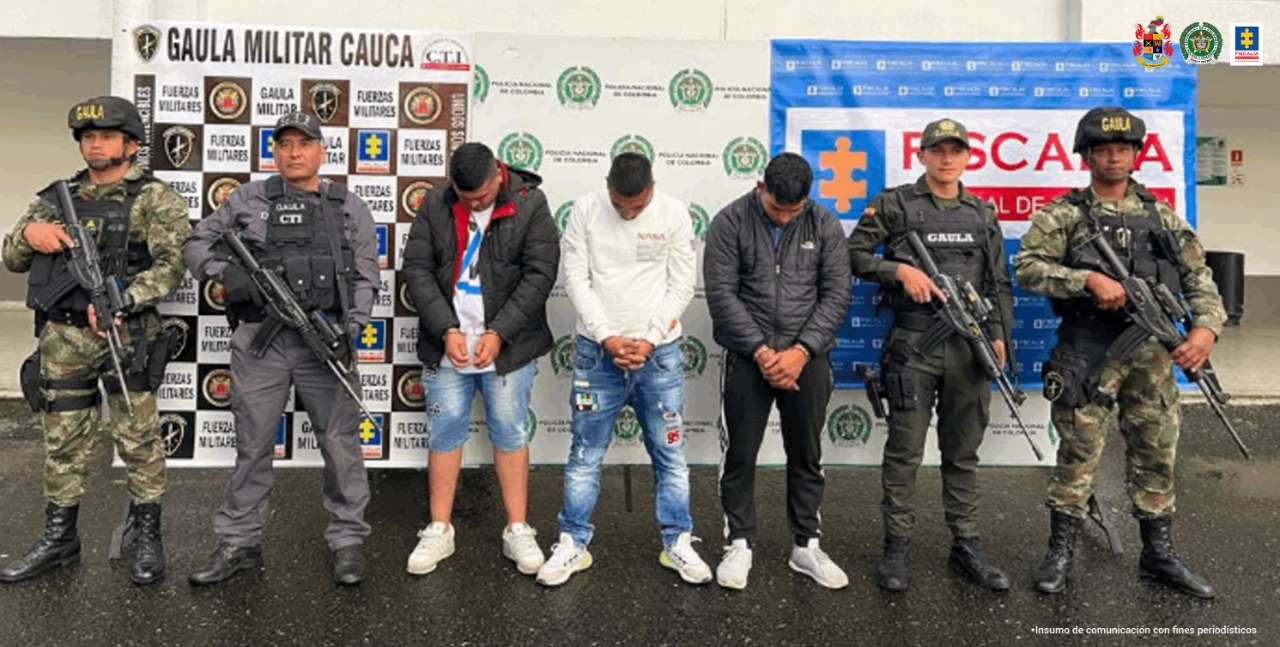 En la foto aparecen de pies, con los brazos adelante y esposados, Edgar Silvio Muñoz; Kevin Esteban Benavídez y Reimon Yovanny Vivas. A lado y lado de ellos hay uniformados del CTI de la Fiscalía, Gaula Policía y Ejército. Detrás de ellos hay tres pendones institucionales del Ejército, Policía y Fiscalía.