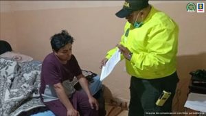 En la foto aparece un presunto integrante del grupo delincuencial Los Hera dentro de una habitación, sentado sobre una cama, con las manos sobre las rodillas. Viste un conjunto color vinotinto. Frente a él hay un uniformado de la Policía Nacional quien tiene un documento en sus manos y se lo enseña a quien está sentado sobre la cama.