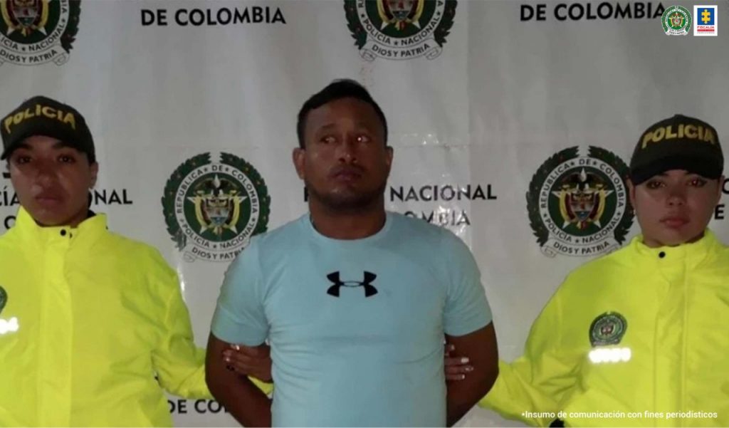 En la fotografía se ve al capturado de camisa azul acompañado de dos uniformados de la Policía Nacional.