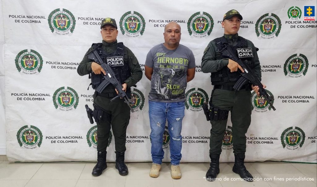 En la imagen aparece una persona detenida, de suéter gris, entre dos uniformados de la Policía Nacional.