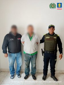 En la imagen aparece una persona de buso gris entre dos uniformados de la Policía y el CTI.