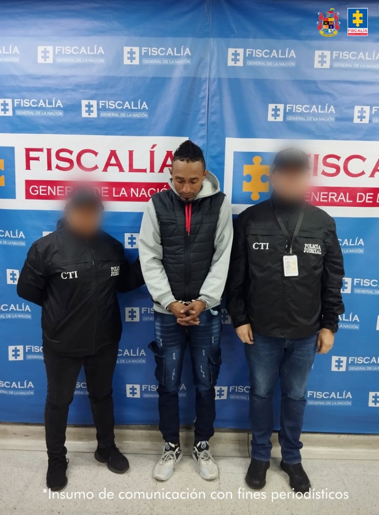 En la imagen aparece una persona detenida, de jean, buso gris y chaleco negro, entre dos uniformados del CTI.