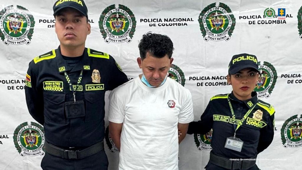 En la imagen aparece una persona de suéter blanco entre dos uniformados de la Policía Nacional. 