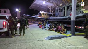 En la fotografía se evidencia a los capturados sentados delante de una embarcación de la Armada Nacional y a los uniformados que los acompañan.
