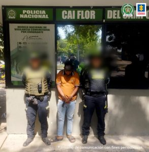 En la fotografía aparece un hombre moreno en el CAI Flor, está de pie, con la cabeza agachada y las manos adelante esposadas, vestido de camiseta amarilla, jean azul, sandalias grises, custodiado por uniformados de la Policía Nacional.
