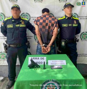En la fotografía están dos hombres morenos, jóvenes, sentados en un escritorio de madera, con micrófonos, en el interior de una sala asistiendo a las audiencias de control de garantías. 
