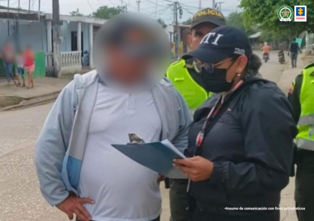 En la fotografía se observa a un uniformado del CTI leyendo los derechos del capturado quien viste una camiseta blanca. En el fondo se observa a un uniformado de la Policía Nacional.