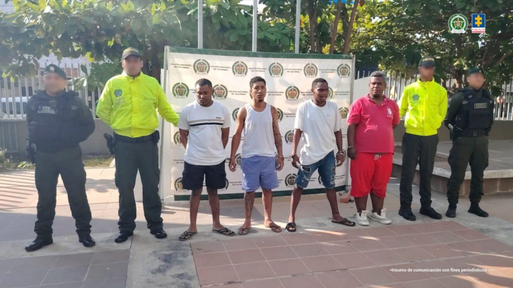 En la fotografía aparecen los medios cuerpos de cuatro hombres morenos, de contexturas gruesas de cabellos cortos negros. Se encuentran sentados al interior de una oficina asistiendo virtualmente a la audiencia en la que se les procesó.