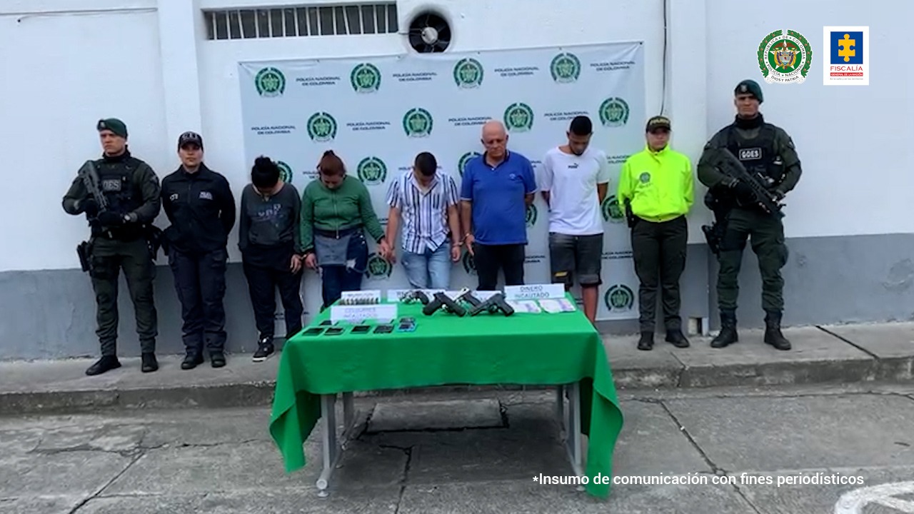 En la foto aparecen de pie y con la cabeza agachada, los presuntos integrantes de ‘Los Financieros’. Al lado derecho de ellos, hay uniformados del CTI de la Fiscalía y de la Policía. Al lado izquierdo de ellos hay dos uniformados de la Policía. Detrás de ellos hay un pendón institucional de la Policía Nacional.