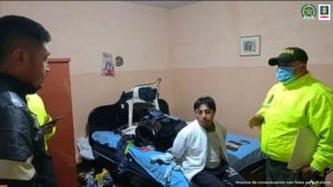 En la foto aparece otro presunto integrante de ‘Los Hera’, en una habitación, sentado sobre una cama con los brazos atrás. Viste un buzo claro y pantalón oscuro. Frente a él hay un uniformado de la Policía Nacional. Sobre la cama se ven varias prendas de manera desordenada.