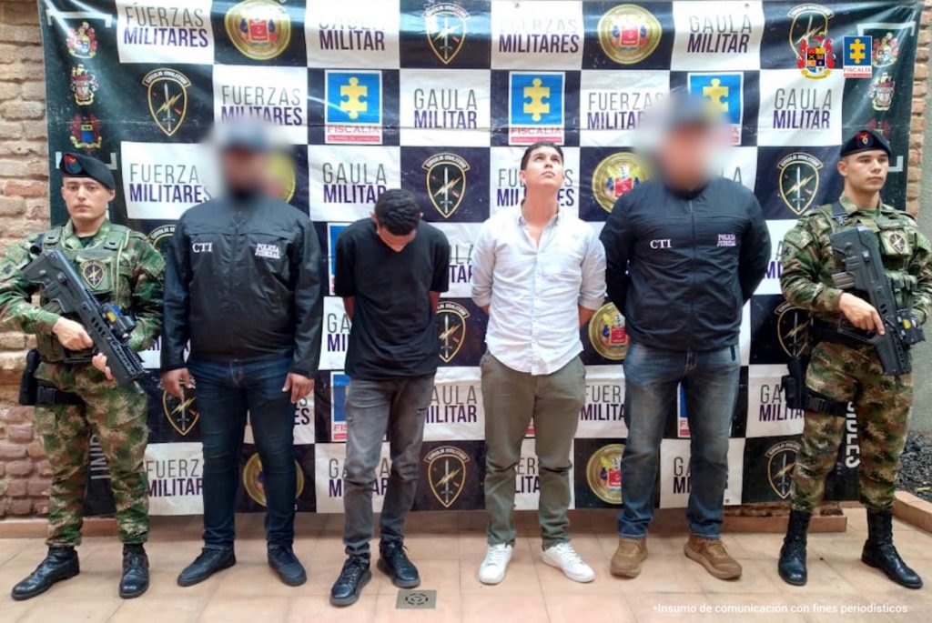 En la fotografía se aprecia de pie y con los brazos a atrás a Luis Anderson Paz Castillo y Andrés Felipe Herrera Jiménez. A sus extremos hay servidores del CTI de la Fiscalía y uniformados del Ejército. Detrás de ellos hay un pendón con logos del Gaula Militar y de la Fiscalía.