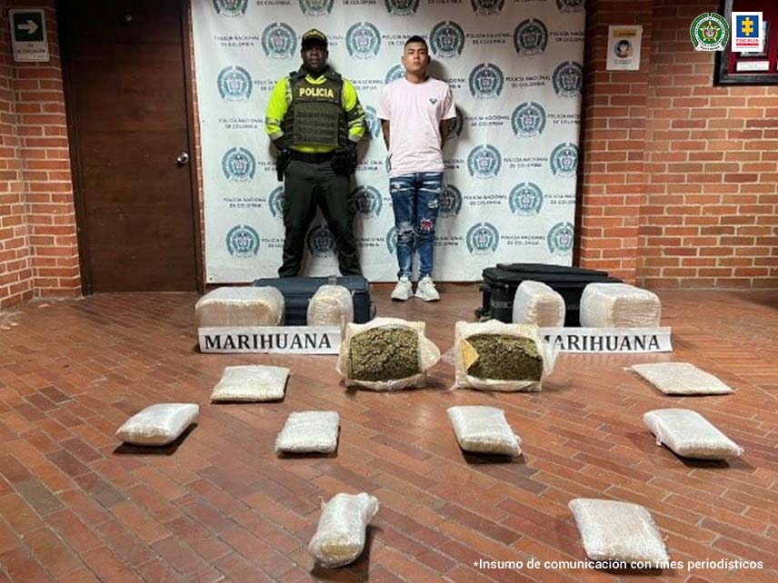 En la foto aparece de pie con los brazos atrás, Michael Daniel Rivera Velazco. Viste camiseta blanca de manga corta, jean azul y tenis blancos. A su derecha hay un uniformado de la Policía Nacional. Delante de ellos, en el piso hay varios paquetes con dos letreros que dicen: ‘Marihuana’. Detrás de ellos hay un pendón institucional de la Policía.