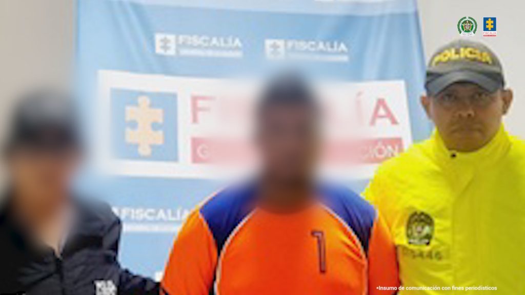 En la imagen aparece una persona de suéter naranja entre dos uniformados del CTI y la Policía.