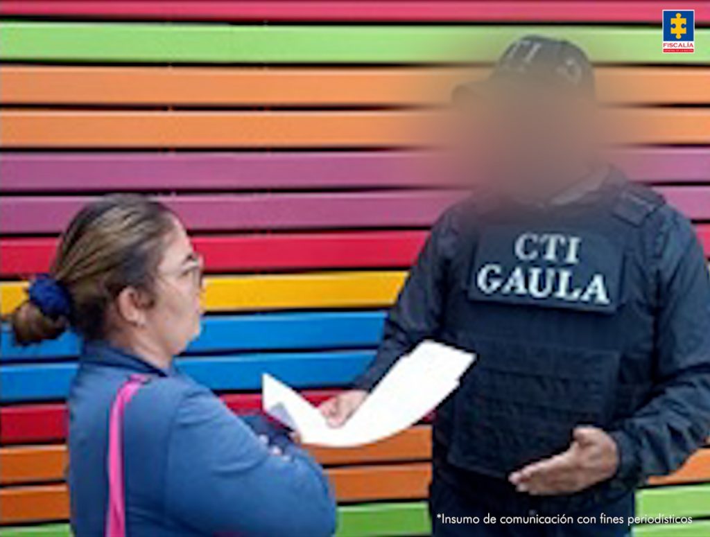 En la imagen aparece una persona de suéter azul, frente a un uniformado del CTI de la Fiscalía.