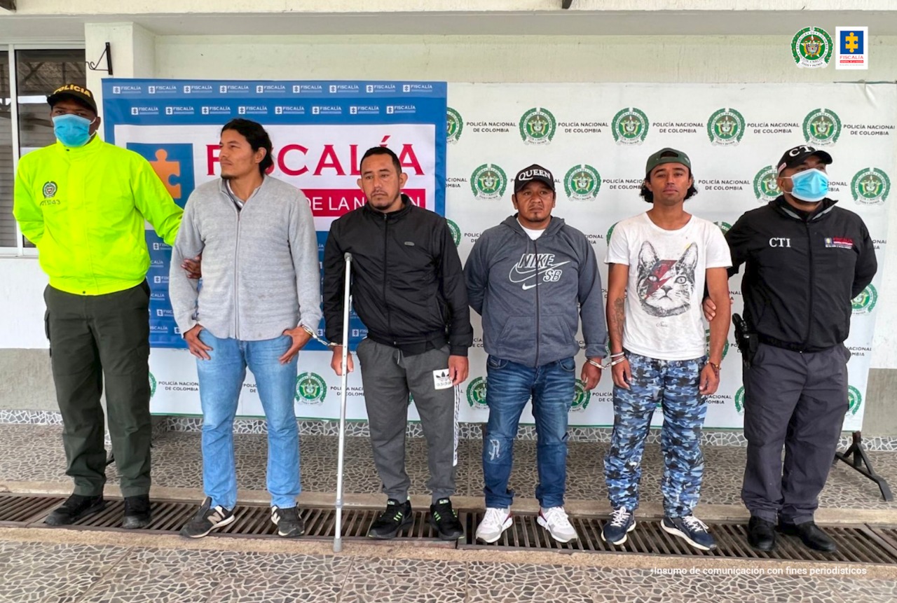 En la foto aparecen de pie, cuatro presuntos integrantes de ‘Los Sin Techo’, uno de ellos sostiera a su lado derecho una muleta. Al lado derecho de ellos hay un uniformado de la Policía Nacional y al lado izquierdo un servidor del CTI de la Fiscalía. Detrás de ellos hay dos pendones institucionales de la Fiscalía y la Policía Nacional.