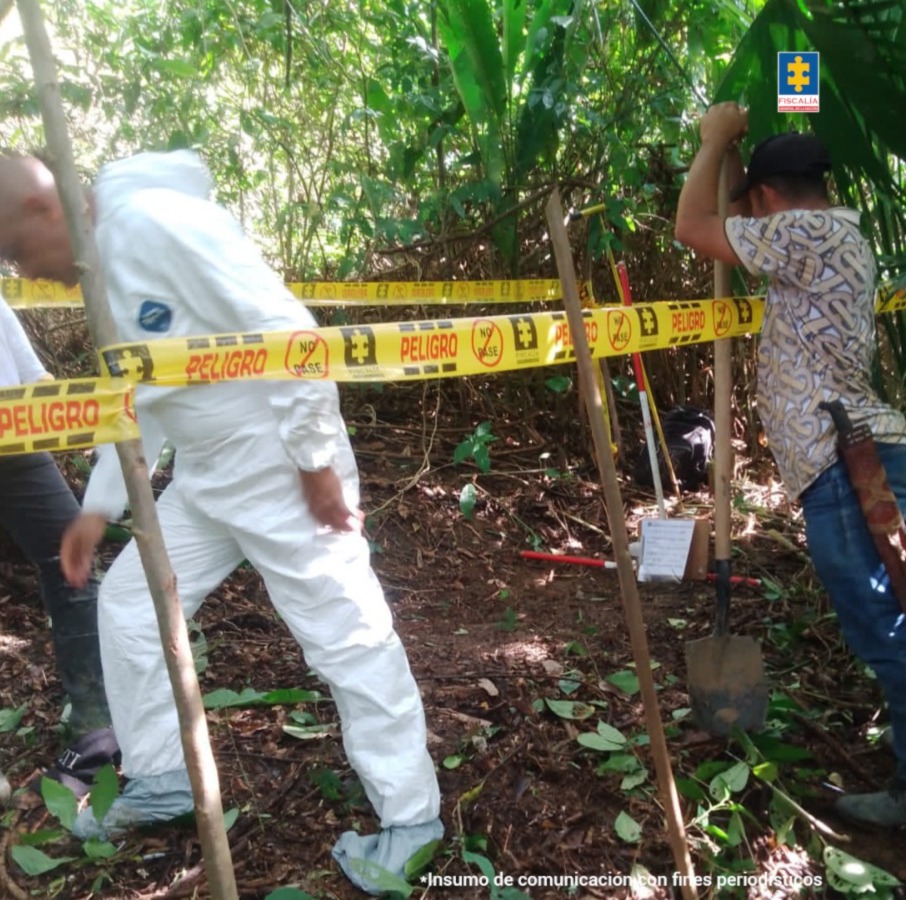En la imagen están funcionarios de la Fiscalía en un terreno con cinta amarillas que demarcan el sitio donde se realizará la exhumación. También aparece un hombre con pala y machete que es el encargado de retirar la maleza del sitio.