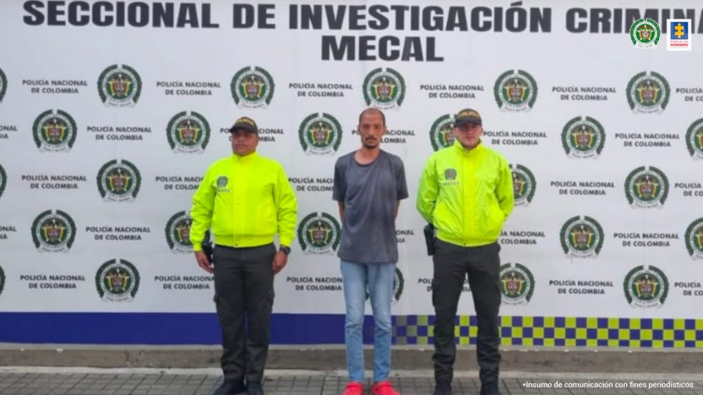 En la fotografía se aprecia a Andrés Fernando Castillo Mosquera, de pie y con los brazos atrás. Viste camiseta de manga corta de color gris oscuro, jean azul y zapatillas rojas. A lado y lado de él hay uniformados de la Policía Nacional. Detrás de ellos hay un pendón institucional de la Policía.