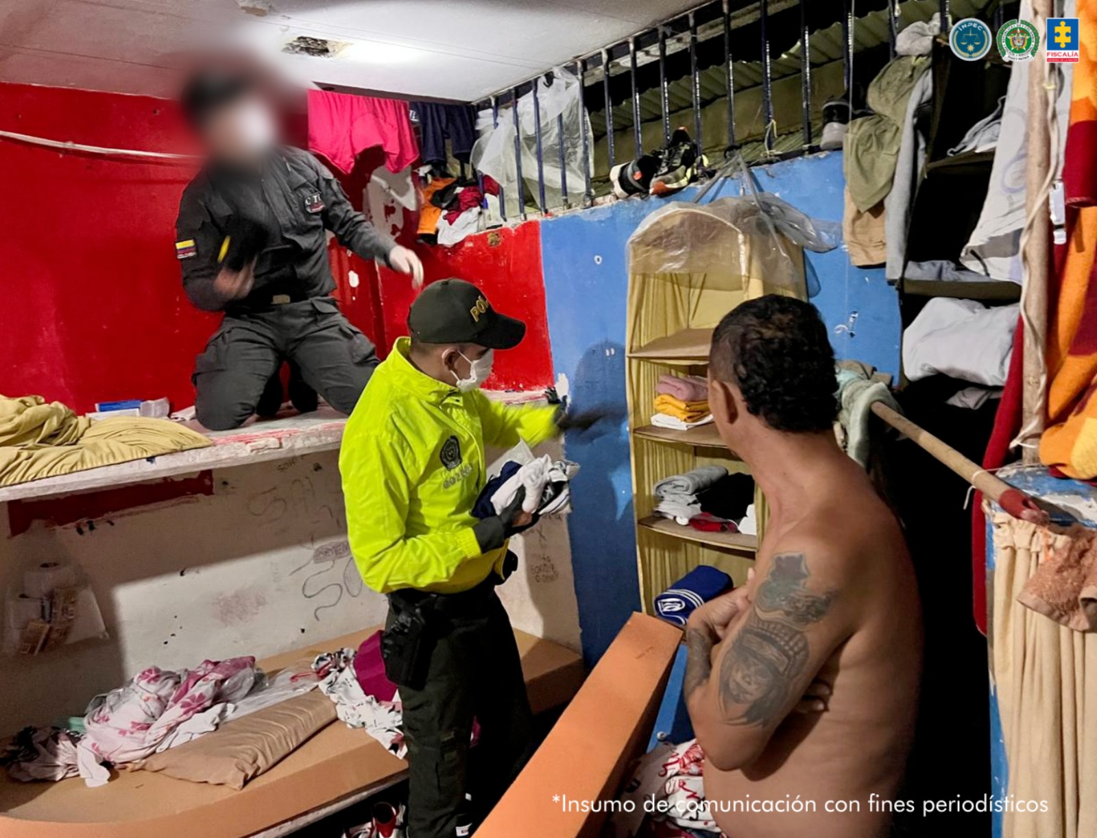 En la imagen se ven miembros de la Policía y el CTI de la Policía. Además se ve una persona sin camisa, de espalda. Están en una celda y se ven algunos elementos como un camarote, zapatos y ropa. 