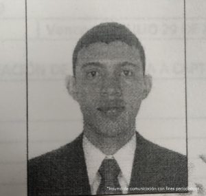 En la imagen está la fotografía en blanco y negro del rostro de un hombre delgado, de ojos, nariz, orejas grandes, cabellos cortos crespos, vestido con saco y corbata.