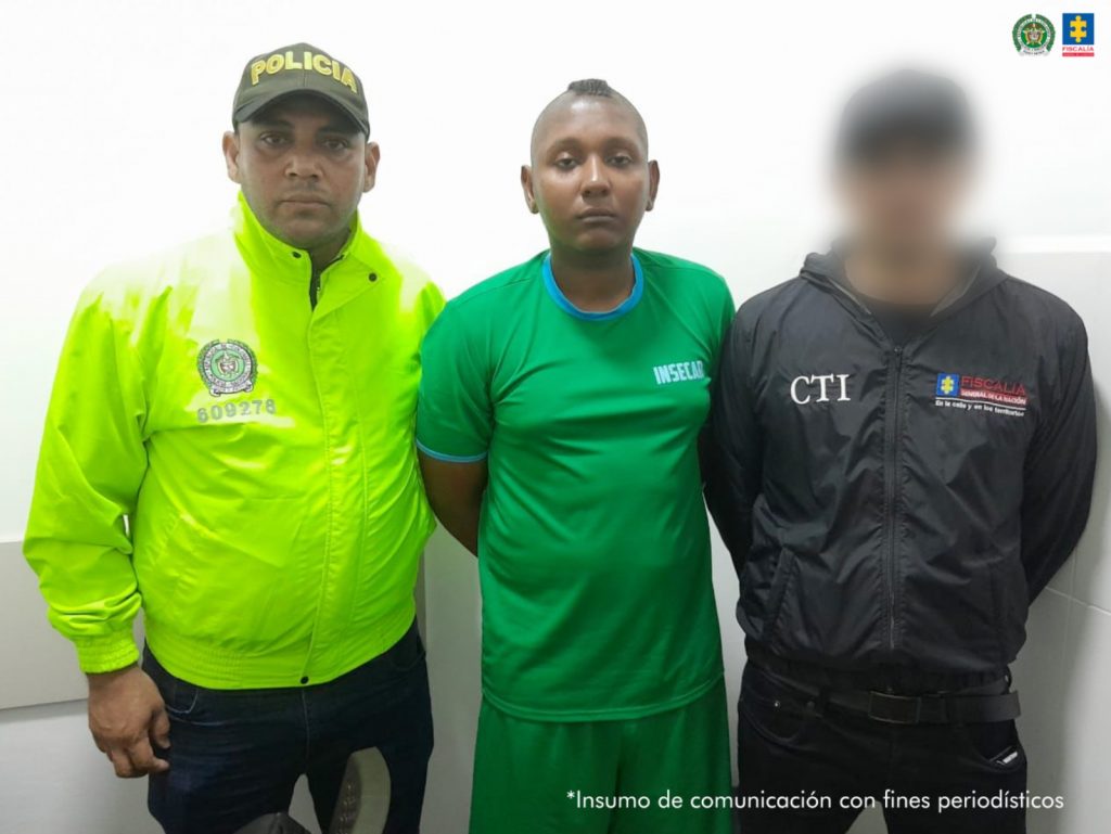 En la imagen un hombre de camiseta verde es capturado por un integrante de la Policía de Carabineros y un integrante del CTI de la Fiscalía General de la Nación.